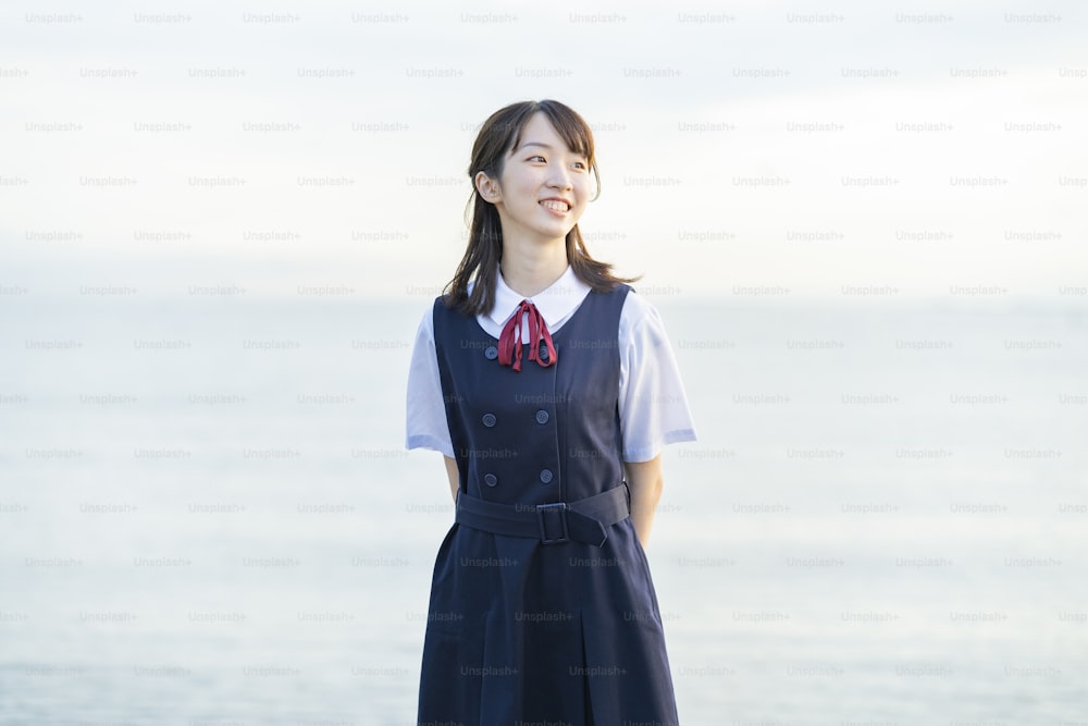 Highschool-Mädchen, das ein Lächeln und den Hintergrund des Meeres zeigt