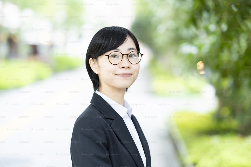Asiatische junge Frau in Anzug und Brille mit Lächeln