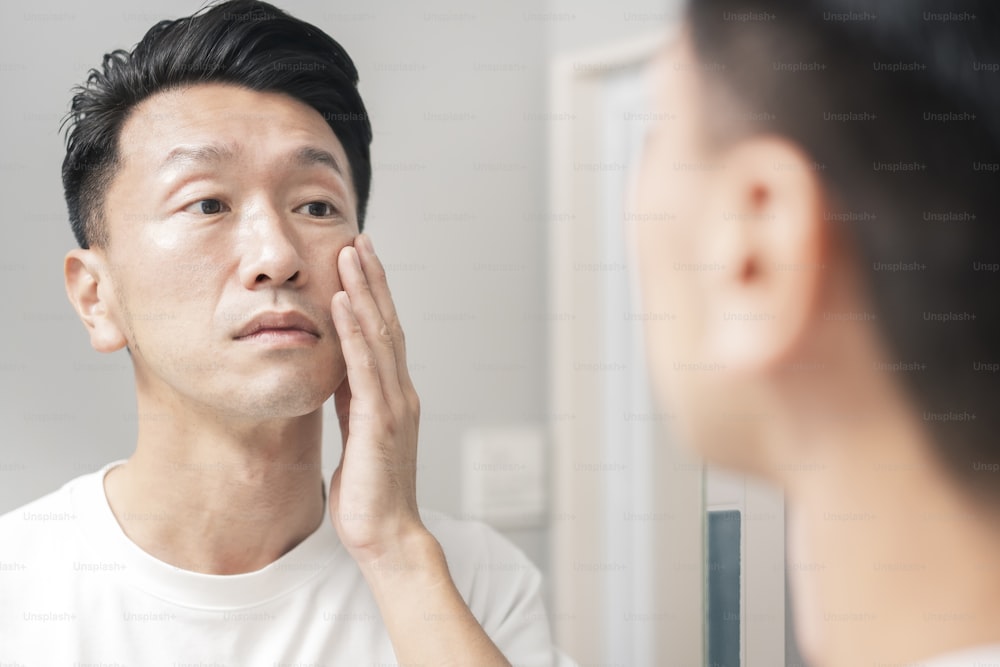 A man who looks in the mirror and checks the condition of his skin