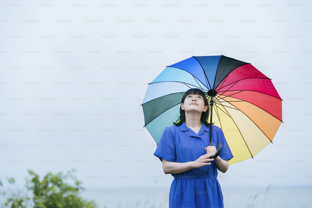 Uma mulher segurando um guarda-chuva colorido na chuva