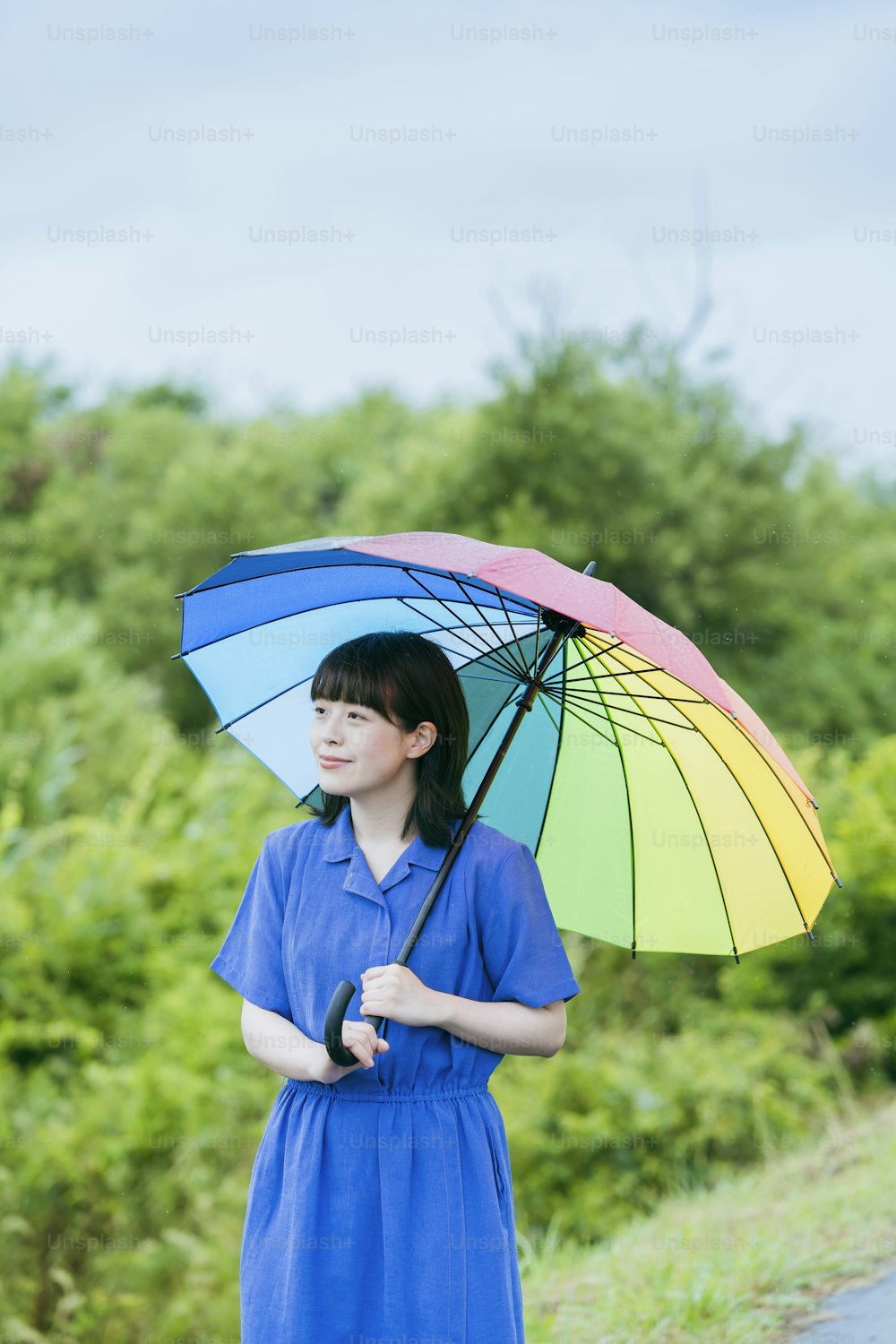 Eine Frau, die einen bunten Regenschirm im Regen hält