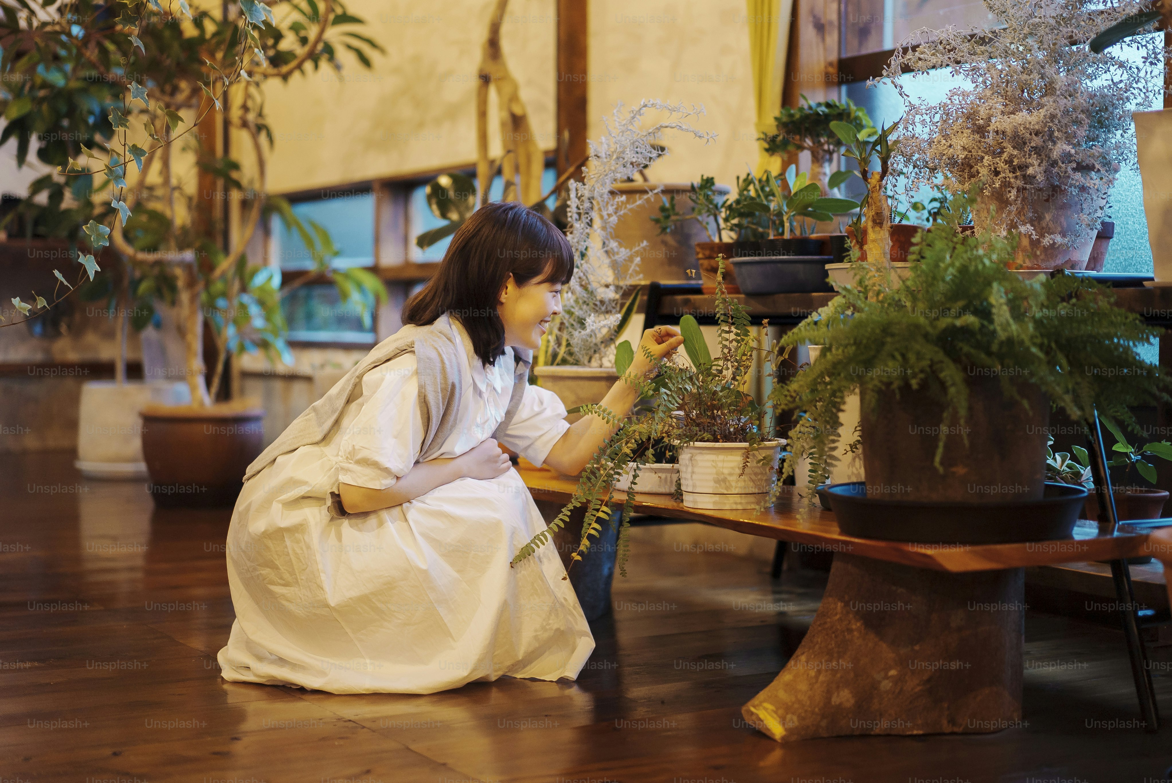 A young woman looking at the foliage plants with a smile