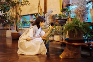 Una mujer joven mirando las plantas de follaje con una sonrisa