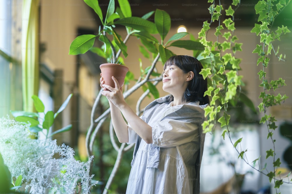 Une jeune femme regardant les plantes à feuillage avec un sourire