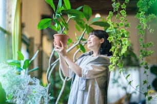 Eine junge Frau, die mit einem Lächeln auf die Laubpflanzen schaut