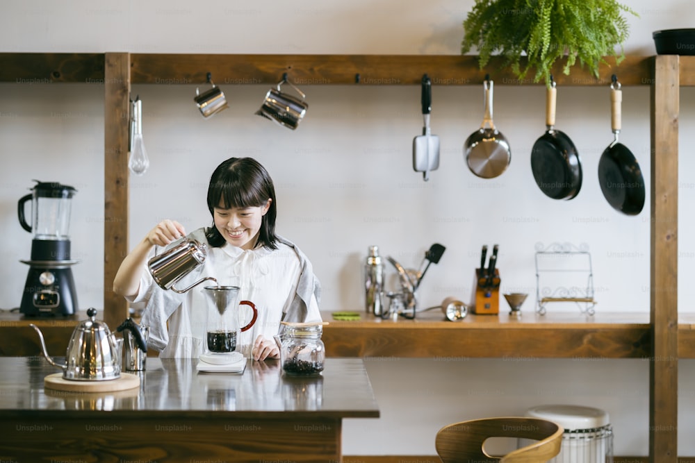 Uma mulher jovem que prepara o café em um espaço relaxante