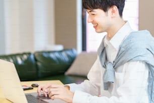 Joven asiático usando una computadora portátil en una habitación informal