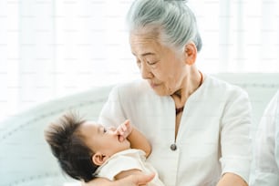 Senior woman holding a baby in a bright room