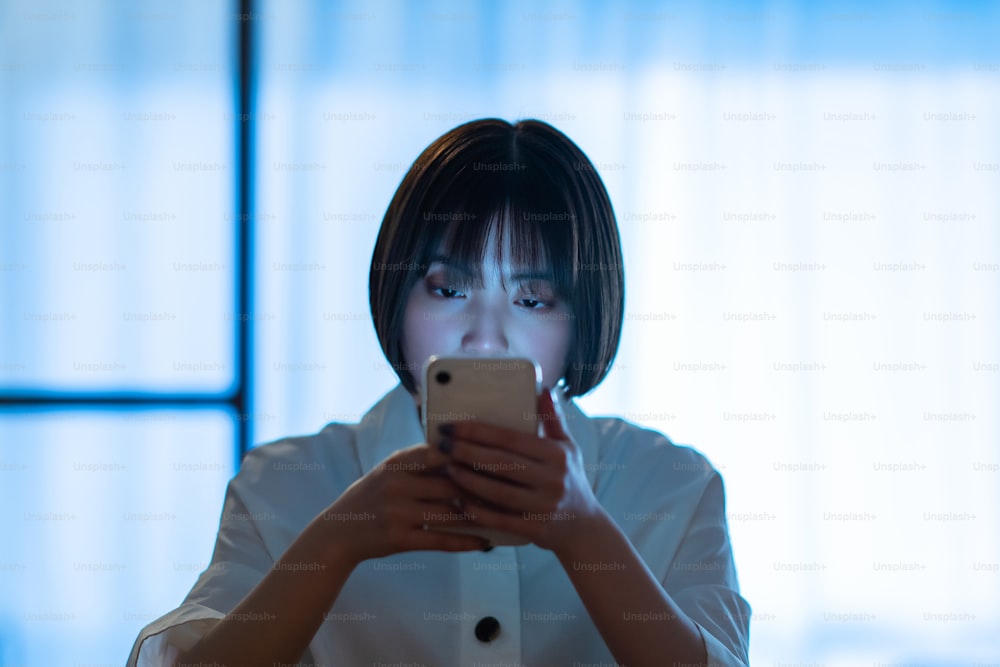 A woman staring at a smartphone with a stern look in the room