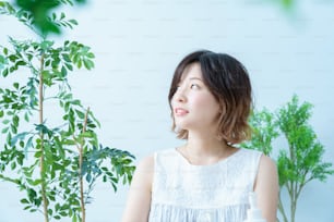 Eine Frau mit einem entspannten Blick, umgeben von Pflanzen