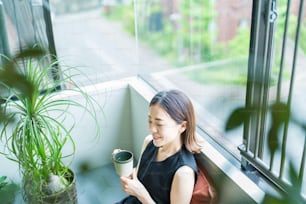 Mujer asiática relajándose rodeada de plantas de follaje