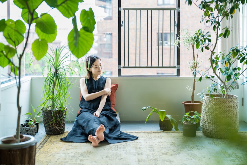 Une femme se relaxant entourée de plantes à feuillage dans la chambre