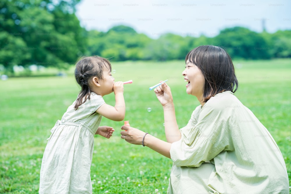 mother and her daughter playing with soap bubbles in the park