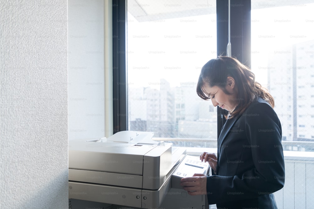 Young asian businesswoman using copying machine.