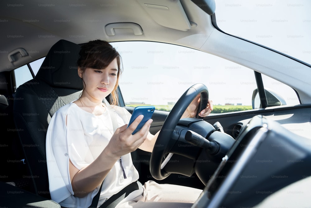 young female driver using smart phone at the wheel.