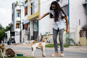 Giovane ragazza adolescente che gioca con i cuccioli di strada indiani