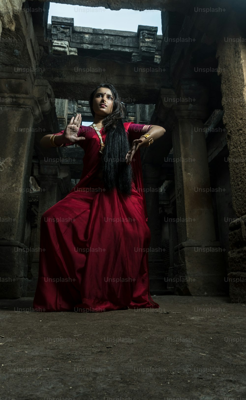 Belle danseuse indienne dans la posture de la danse indienne. Danse classique indienne bharatanatyam. Fille portant un sari rouge indien traditionnel, des bijoux en or et des bracelets. Concept de tournage Maa Durga