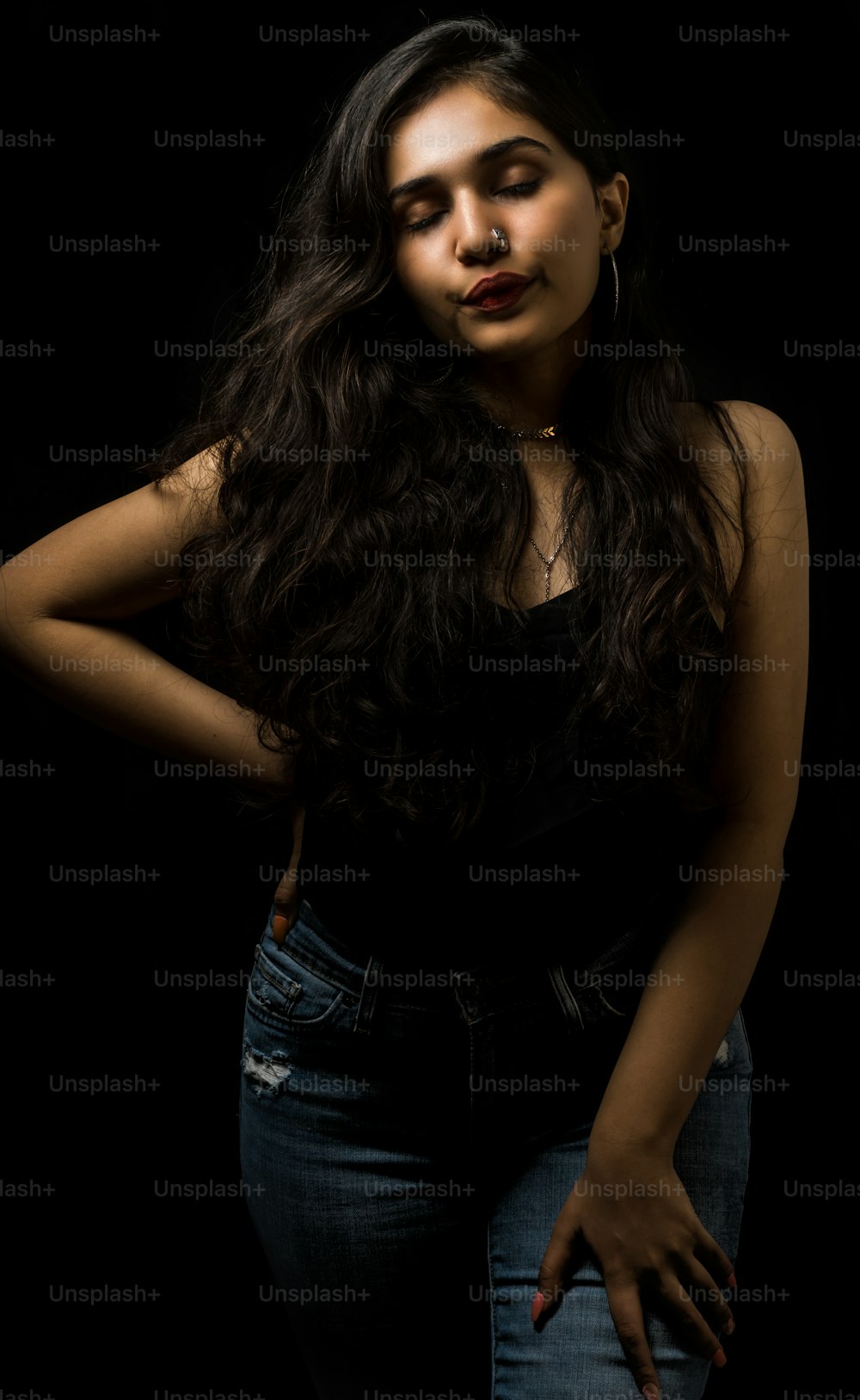 Sexy Frau mit Make-up und modischer Frisur posiert im Studio auf schwarzem Hintergrund