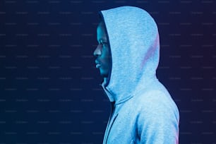 트렌디한 회색 후드티를 입은 아프리카계 미국인 젊은 스포츠맨의 네온 미래형 측면 초상화는 똑바로 앞을 내다보고 있다