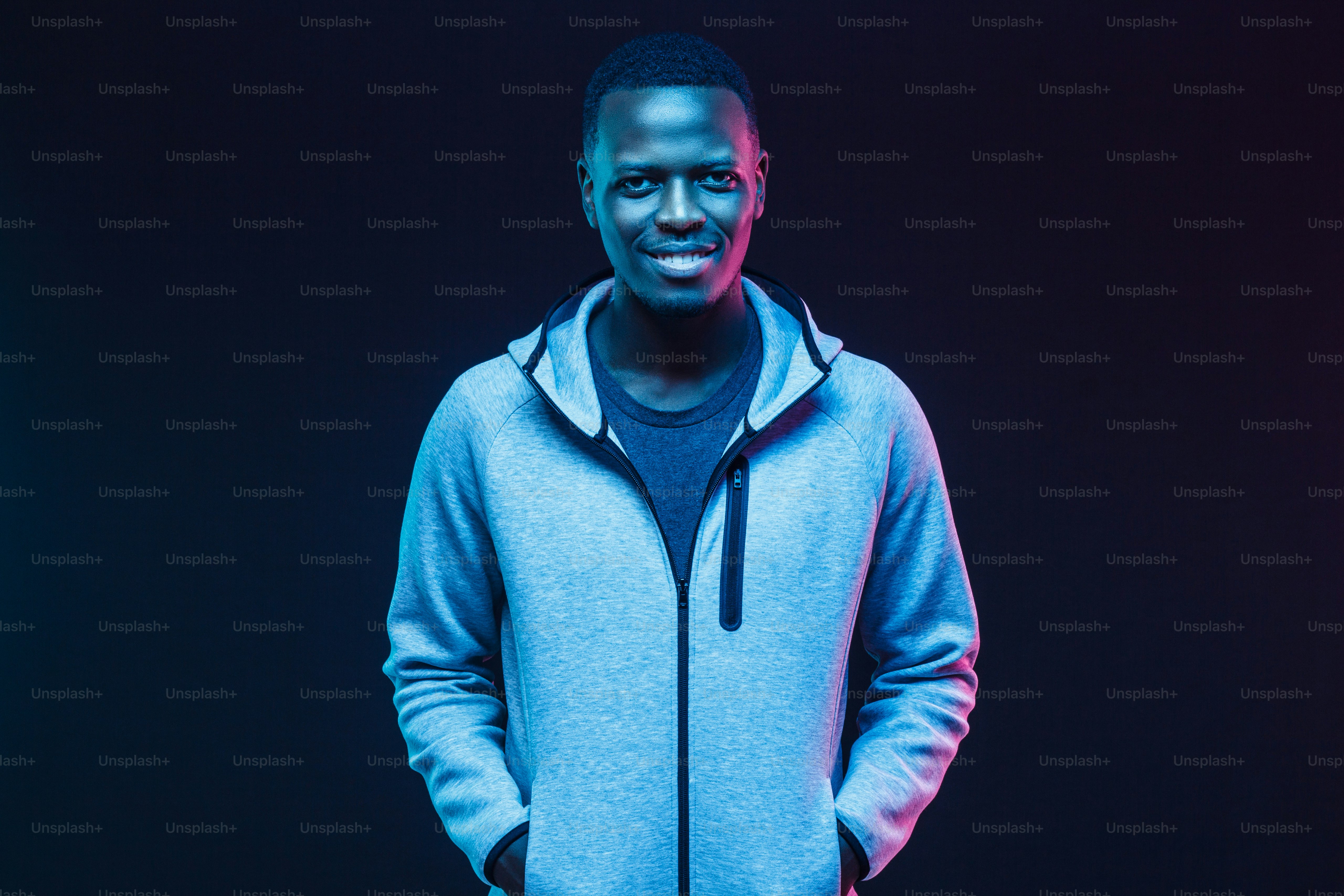 Dark neon portrait of smiling african man  wearing gray hoodie
