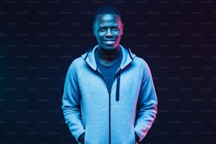Dark neon portrait of smiling african man  wearing gray hoodie