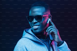 Retrato de neón de un joven africano escuchando música con auriculares inalámbricos
