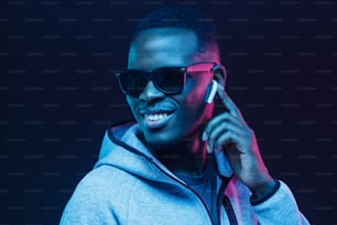 Neon portrait of young african man listening music with wireless earphones