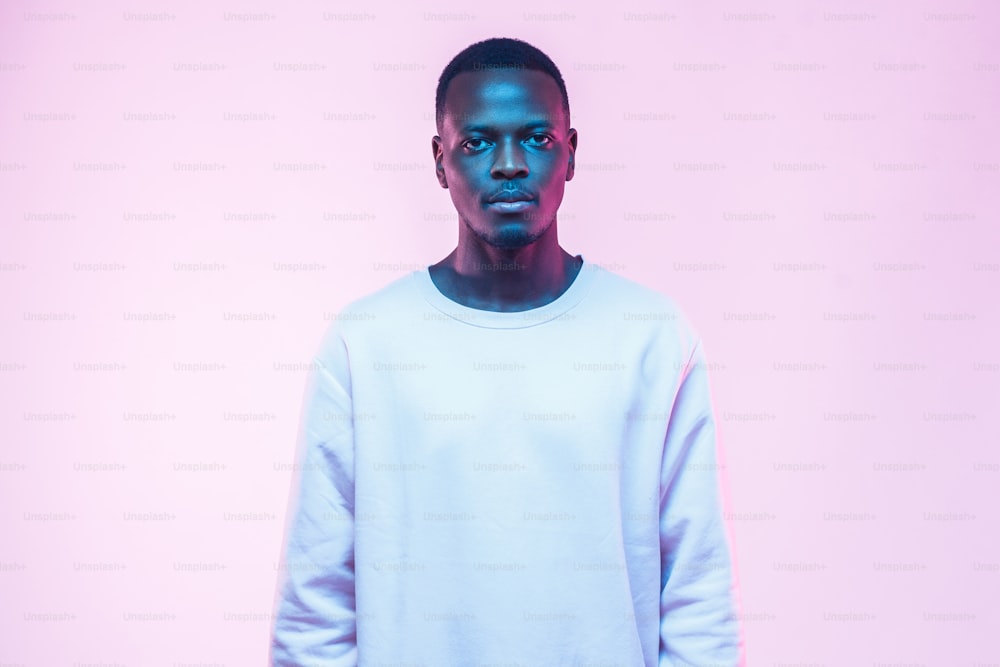 Portrait of young African male isolated on pink background lit by blue light
