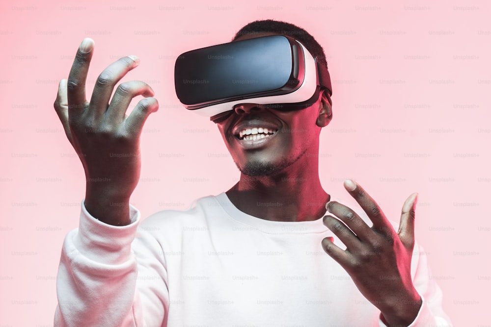 Verblüffter aufgeregter junger Afroamerikaner, der eine intelligente High-Tech-VR-Brille trägt und sich ein 360-Grad-Video ansieht
