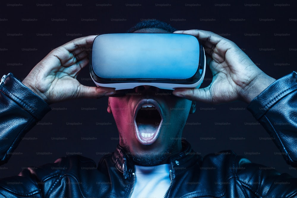 Headshot eines aufgeregten jungen Afroamerikaners, der die virtuelle Realität mit weit geöffnetem Mund genießt