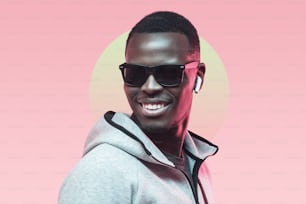 Portrait d’un beau jeune athlète afro-américain écoutant de la musique avec des écouteurs, portant des lunettes de soleil