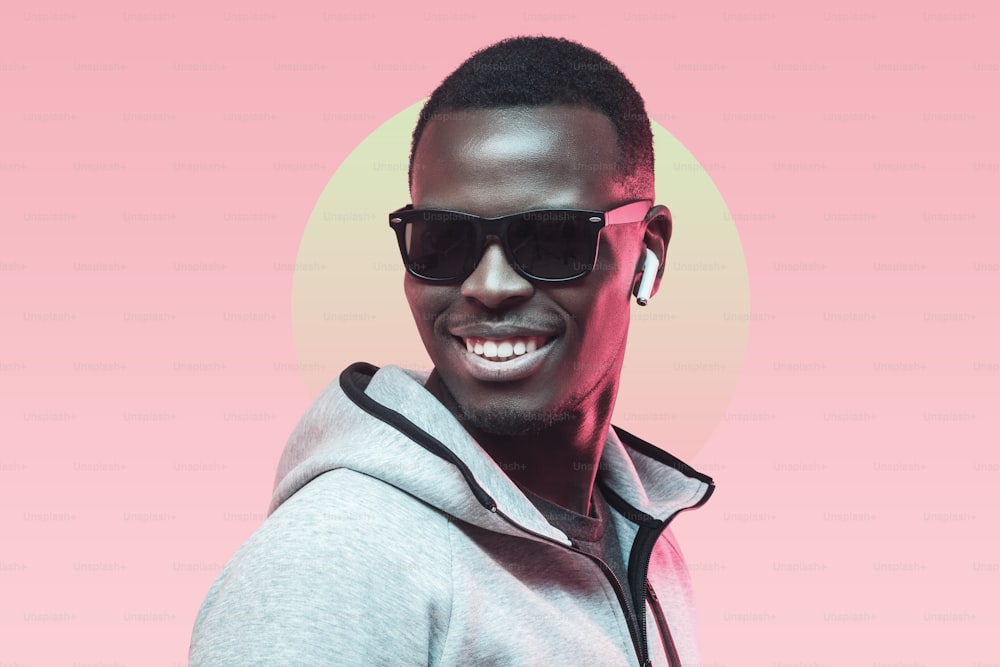 Portrait of handsome young african american athlete listening music with earphones, wearing sunglasses