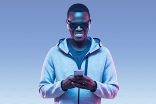 Retrato de un joven afroamericano que usa un teléfono inteligente para escuchar música con auriculares