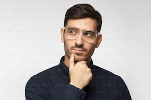 Young man with pensive face thinking of some idea for business isolated on grey background