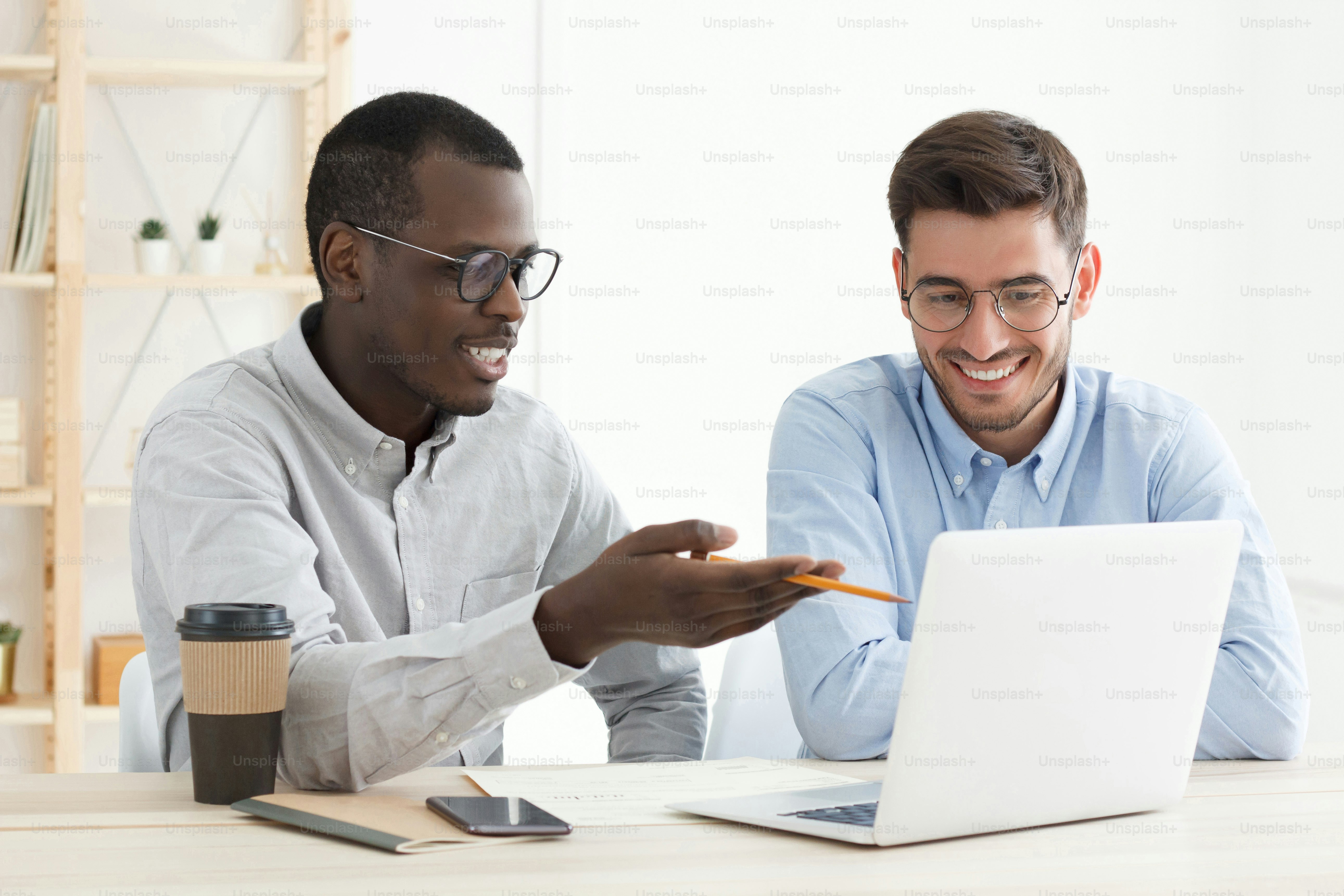 Diversity in education. African male teacher supporting his caucasian adult student while he is doing task using laptop