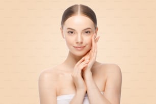 Schönheitsporträt einer Frau oder eines weiblichen Modells, das Händchen in der Nähe des Gesichts mit perfekter sauberer Haut hält, isoliert auf beigem Hintergrund. Hautpflege- oder Kosmetikwerbung.
