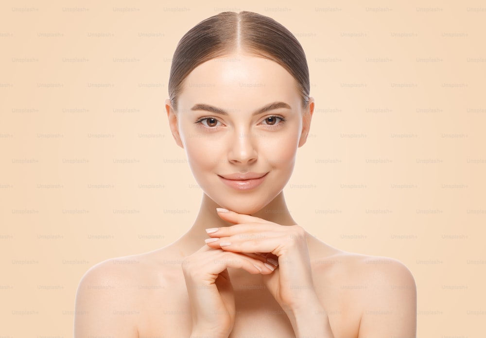 Schönheitsporträt einer Frau oder eines weiblichen Modells, das Händchen in der Nähe des Gesichts mit perfekter sauberer Haut hält, isoliert auf braunem Hintergrund. Hautpflege- oder Kosmetikwerbung.