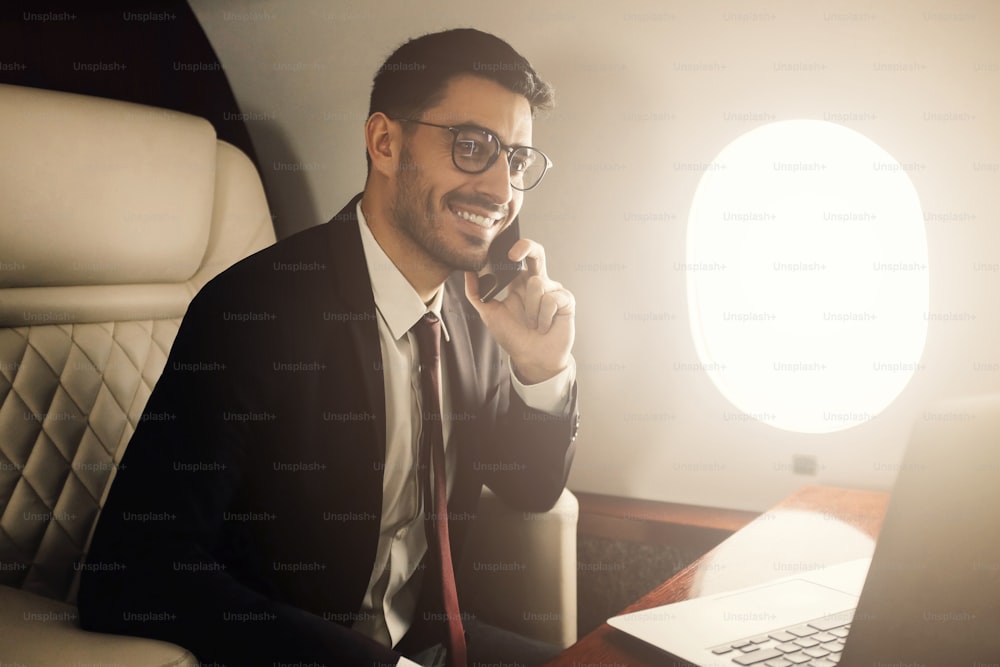 개인 제트기. 부유한 사업가 또는 억만장자가 일등석을 타고 비행기에서 일하며 전화 통화를 한다