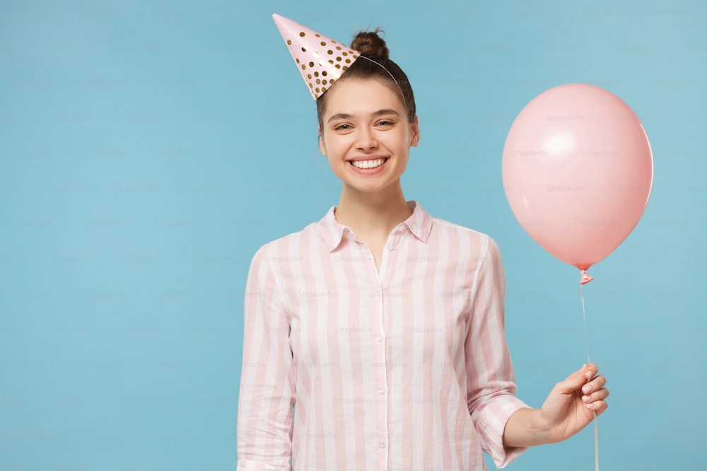 Happy birhday girl celebrating, holding pink balloon, isolated on blue background