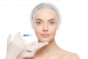 Young woman standing in medical cap, ready to receive beauty injection from cosmetologist, isolated on white background