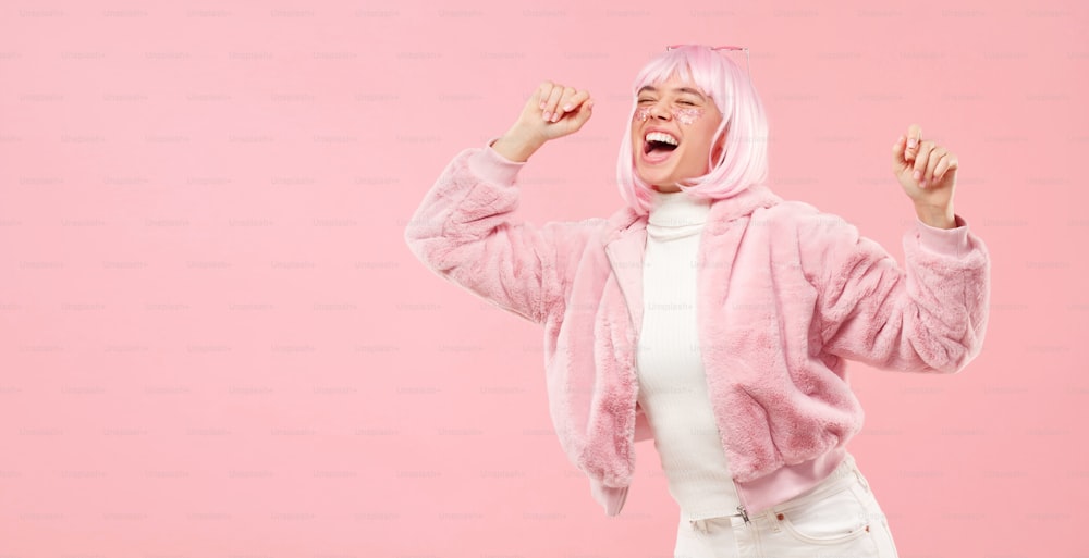 Banner horizontal de adolescente riendo y bailando en una fiesta con los ojos cerrados, aislado sobre fondo rosa con espacio de copia a la izquierda
