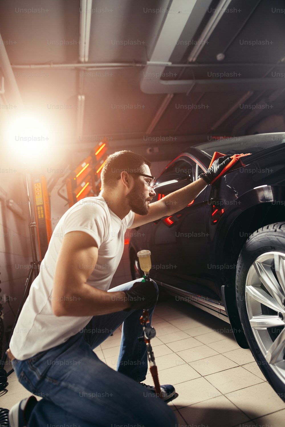 Um homem limpando o carro com pano de microfibra, detalhamento do carro ou conceito de valeting. Foco seletivo.