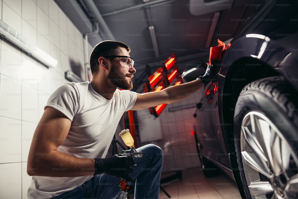 Un homme nettoyant une voiture avec un chiffon en microfibre, un esthétique automobile ou un concept de voiturier. Focalisation sélective.