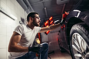 Un hombre limpiando el coche con un paño de microfibra, detalles del coche o concepto de valeting. Enfoque selectivo.