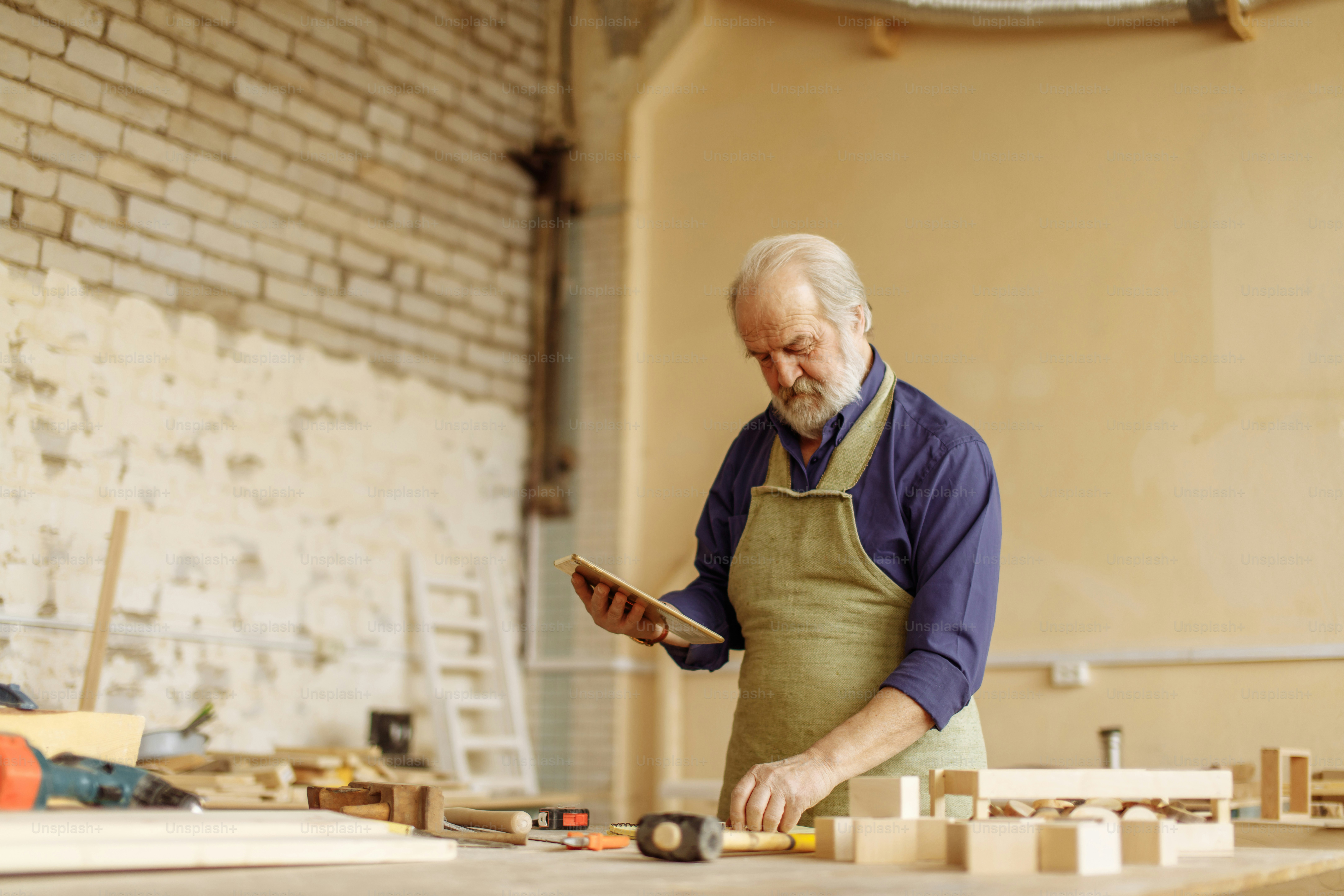 close up side view portrait of old man with grey hair, moustache and beard working with tablet in the garage. copy space