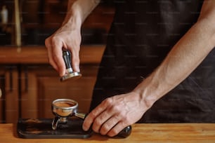 a barista is using a tamper to press coffee seads. close up cropped shot