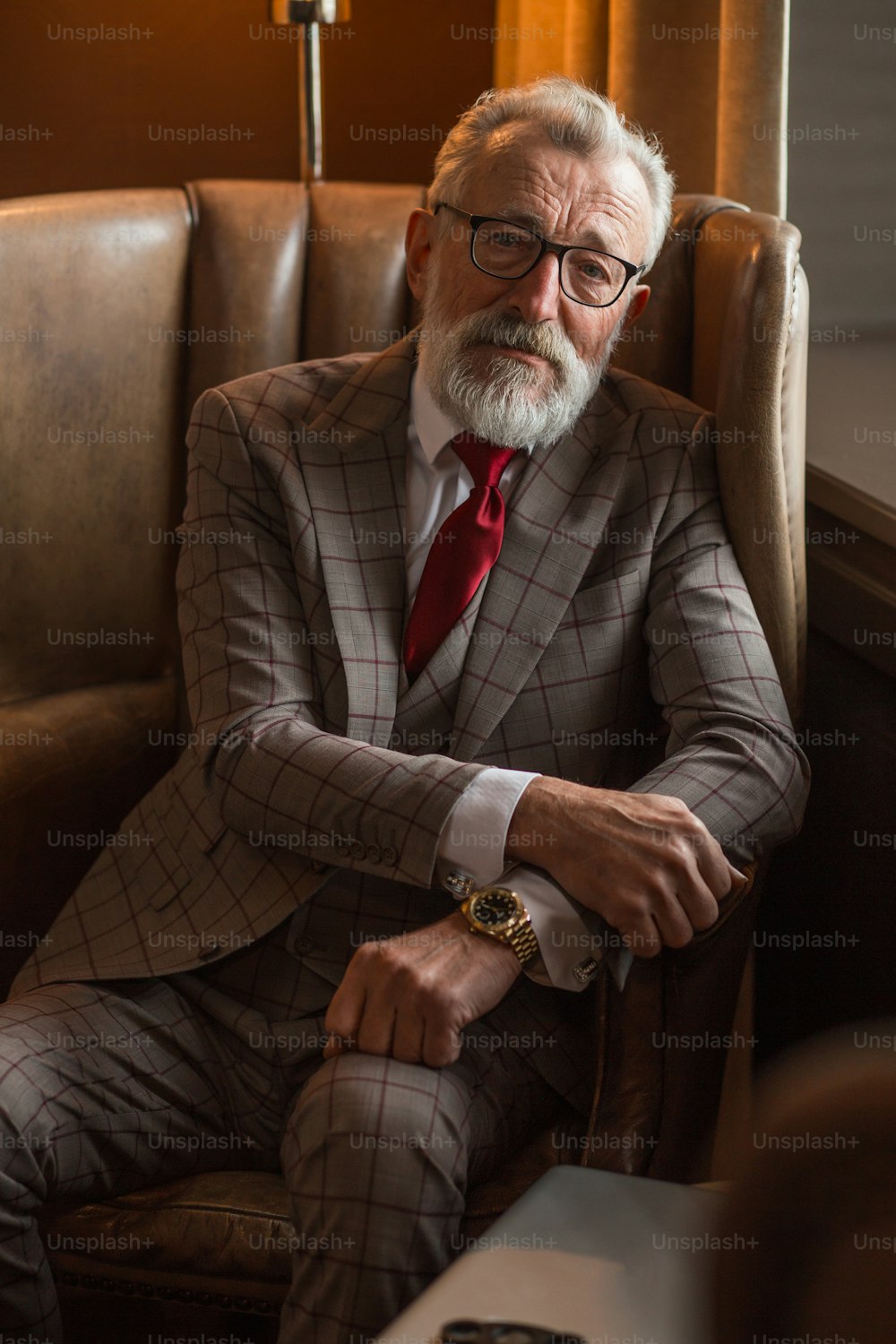 Portrait of chic luxurious trendy wealthy rich sharp well-dressed with burgundy tie and checkered suit intelligent hipster grandpa posing at his luxury home interior.