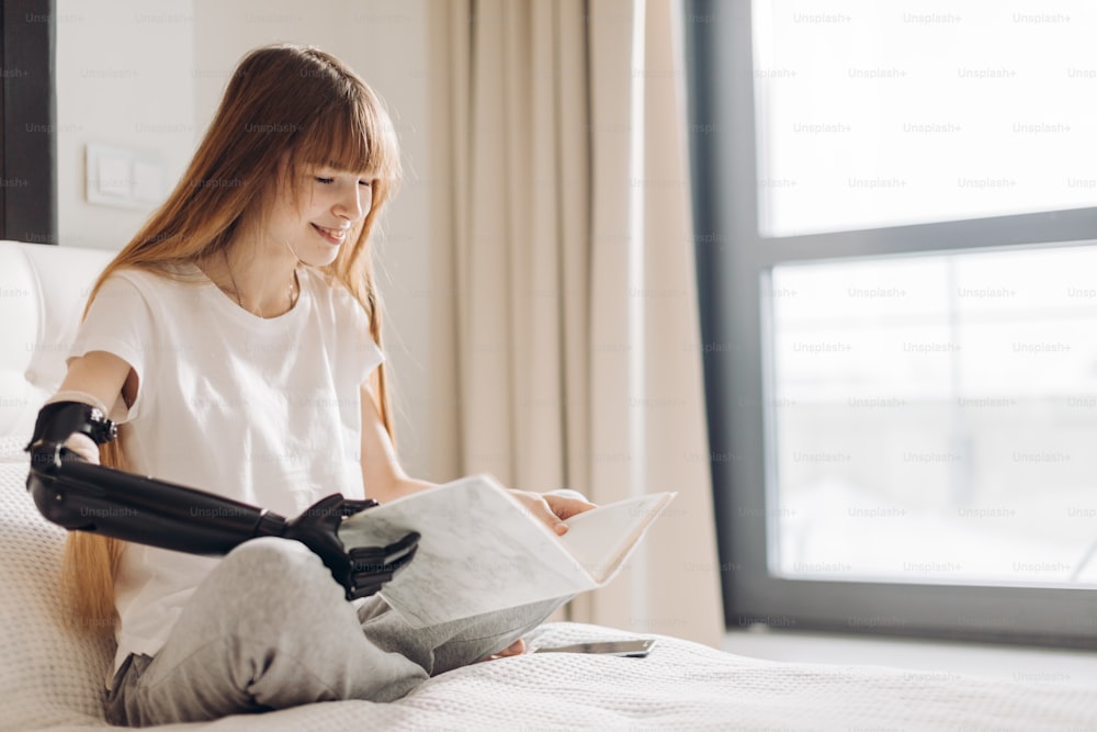 Close-up photo of a beautiful girl holding a book with an artificial arm.close up photo, free time, spare time