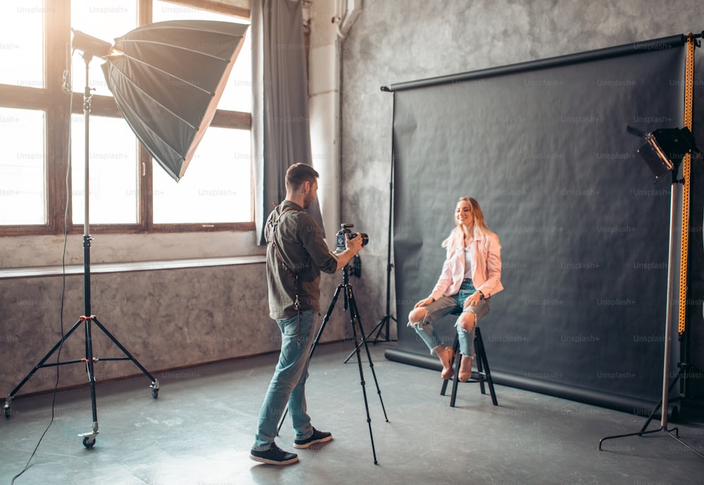 Ragazza positiva che ride alla macchina fotografica allo studio fotografico, scatto laterale