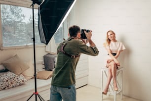 Photographer taking picture of awesome model in professional photo studio, job, occupation, photographer is keen on making pictures